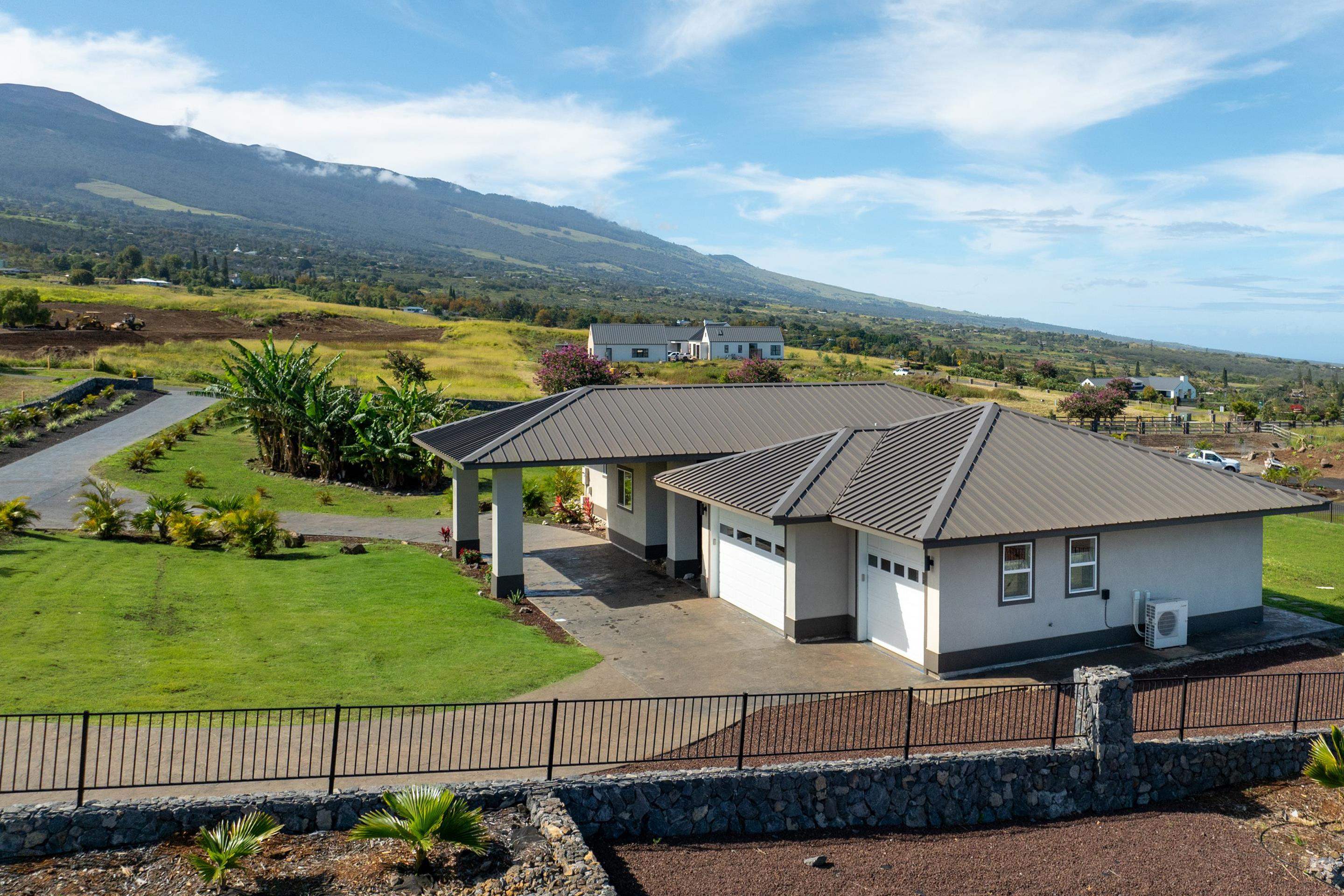 272 Huahua Street Kula, HI 96790 - Photo 5 of 43 a view of a white house next to a yard with wooden fence