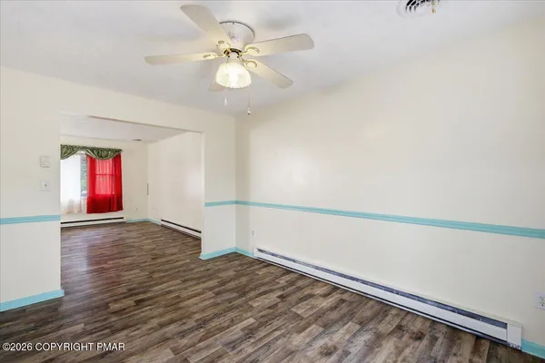 an empty room with wooden floor and fan
