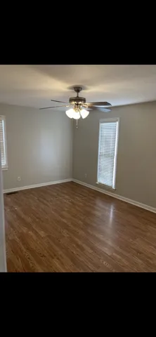a view of wooden floor and a chandelier fan in an empty room