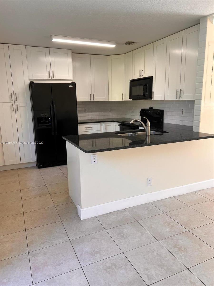 Lakeview Deerfield Beach, FL 33442 - Photo 3 of 14 a kitchen with granite countertop a refrigerator and a stove