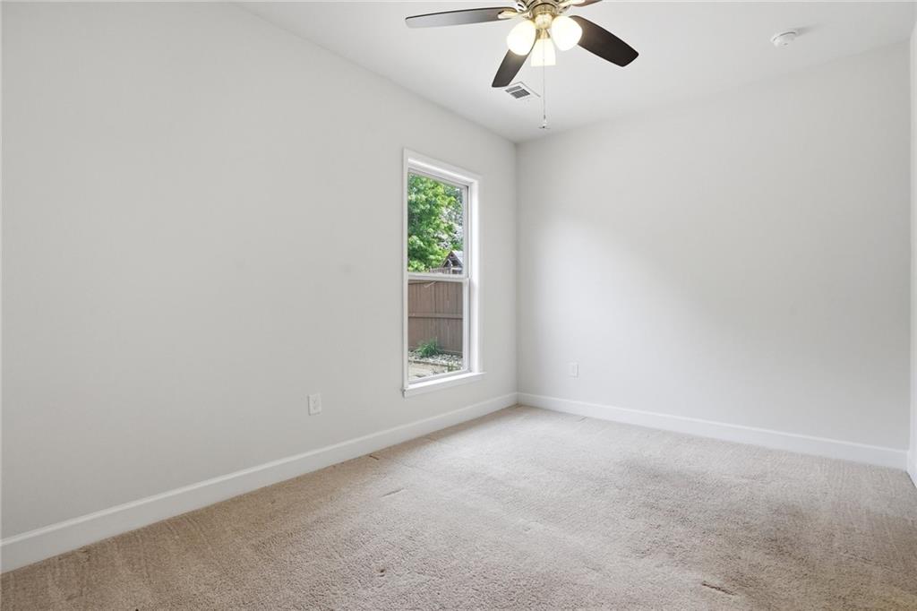3770 Terrasol Trail Southwest Lilburn, GA 30047 - Photo 37 of 63 an empty room with a chandelier fan and windows
