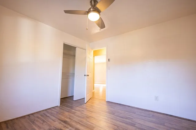 an empty room with wooden floor and a ceiling fan