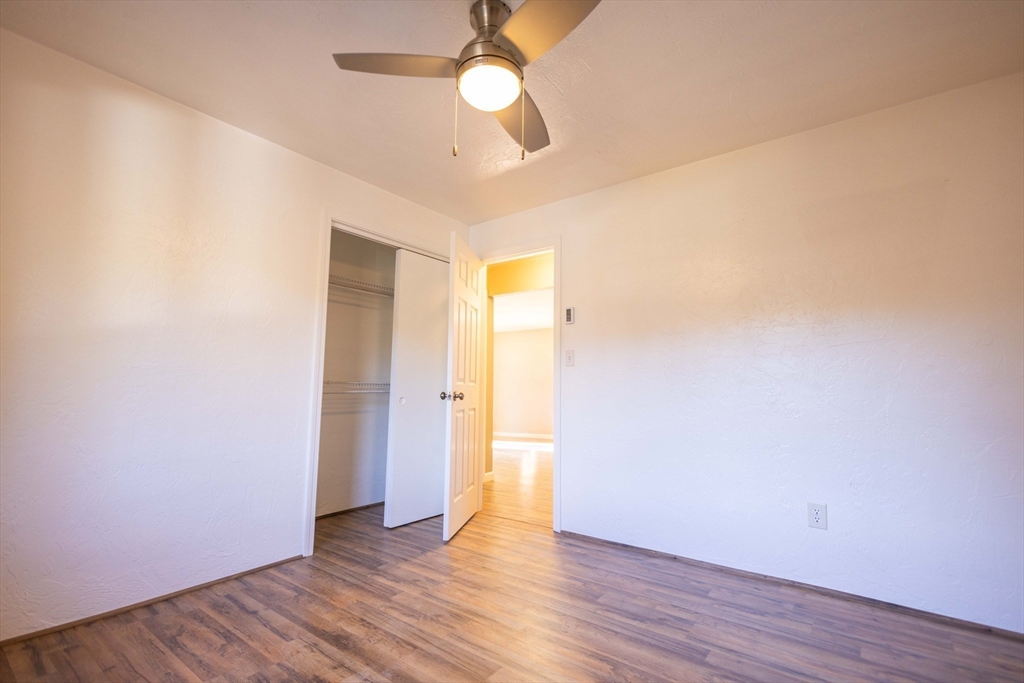 21 Erick Road, Unit 16 Mansfield, MA 02048 - Photo 12 of 28 an empty room with wooden floor and a ceiling fan