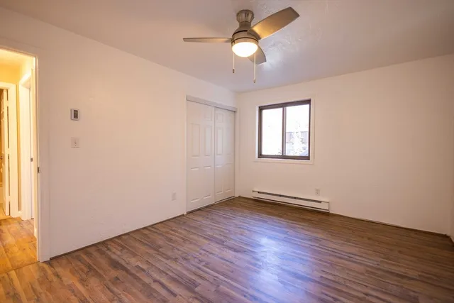 an empty room with wooden floor chandelier fan and windows