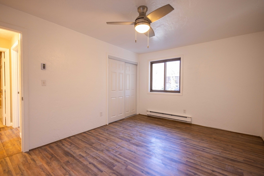 21 Erick Road, Unit 16 Mansfield, MA 02048 - Photo 6 of 28 an empty room with wooden floor chandelier fan and windows