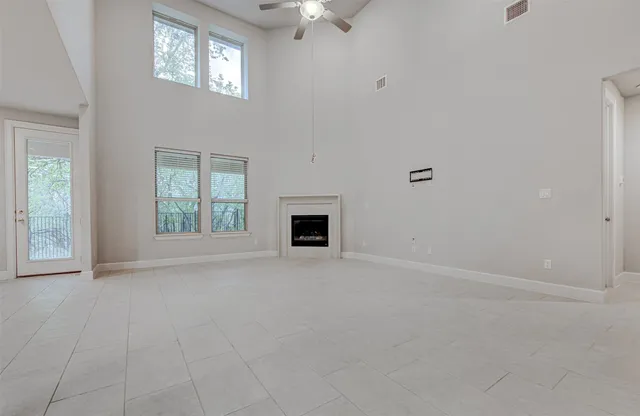 an empty room with windows and fireplace