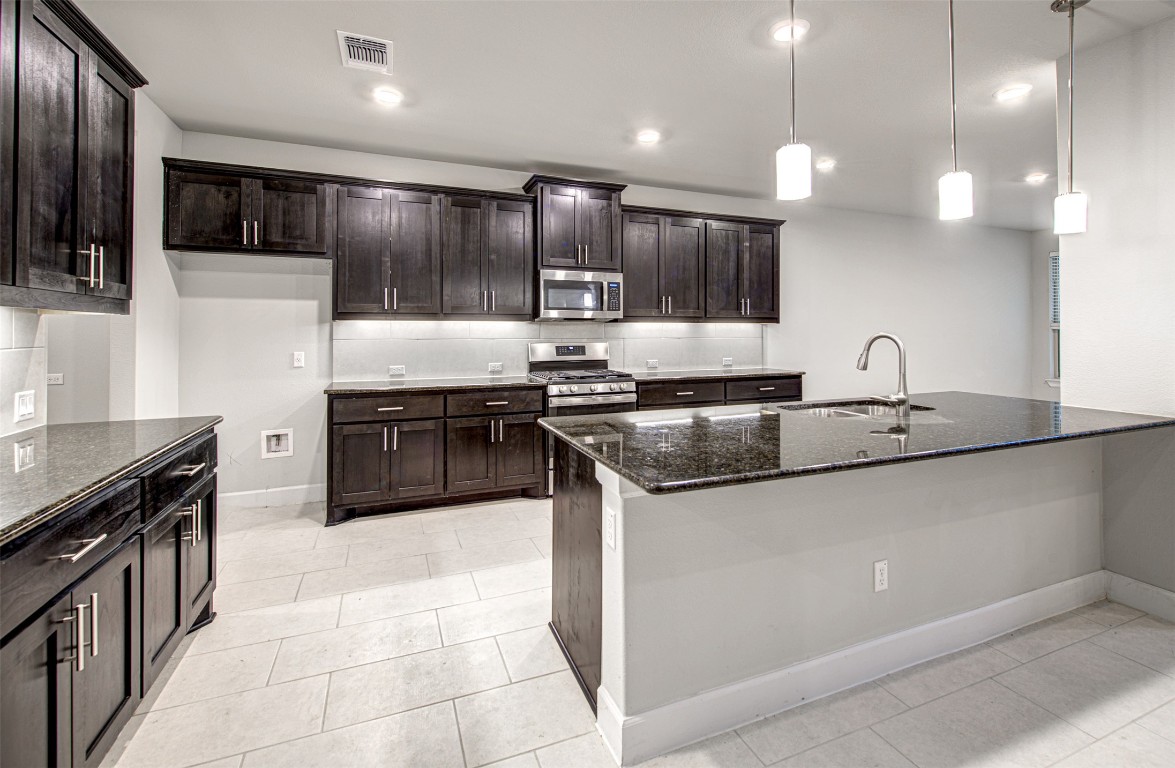 316 Buffalo Ridge Drive Manchaca, TX 78652 - Photo 10 of 37 a kitchen with kitchen island granite countertop a sink and stove