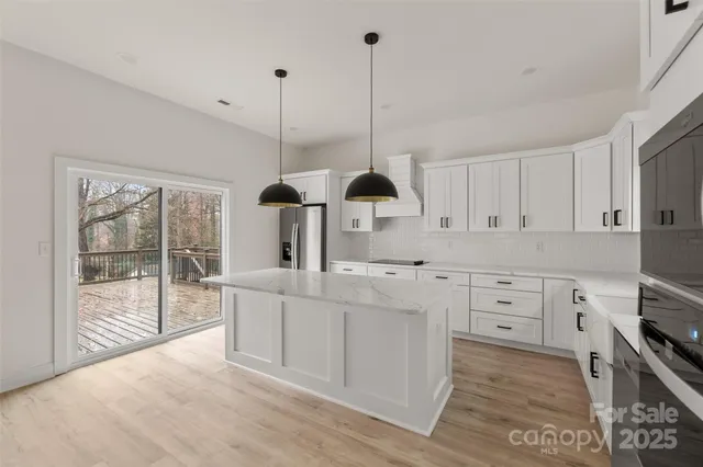 a kitchen with white cabinets and wooden floor