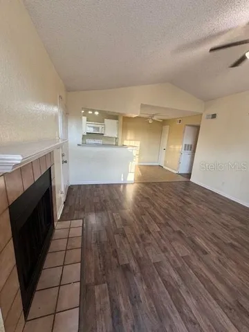 a view of a refrigerator in kitchen and an empty room with wooden floor