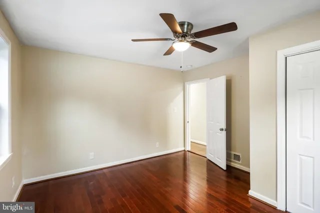 an empty room with wooden floor and ceiling fan