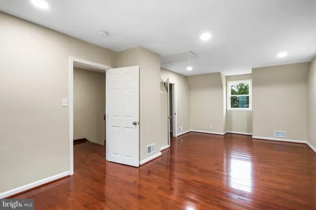 an empty room with wooden floor & windows and bathroom