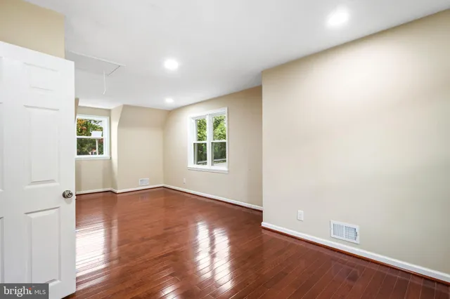 an empty room with wooden floor and windows
