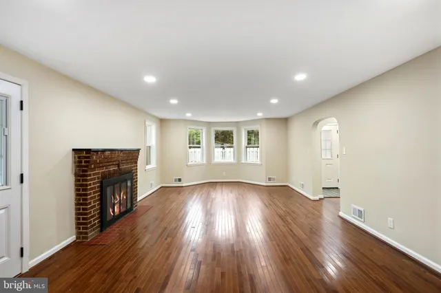 an empty room with wooden floor and fireplace