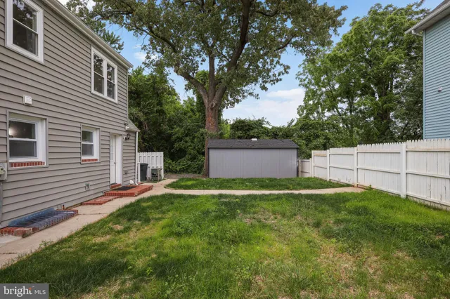 a backyard of a house with plants and large tree