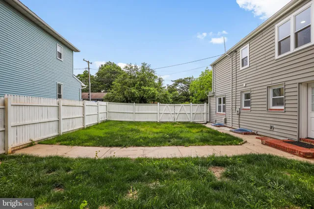 a view of a backyard with plants and white fence