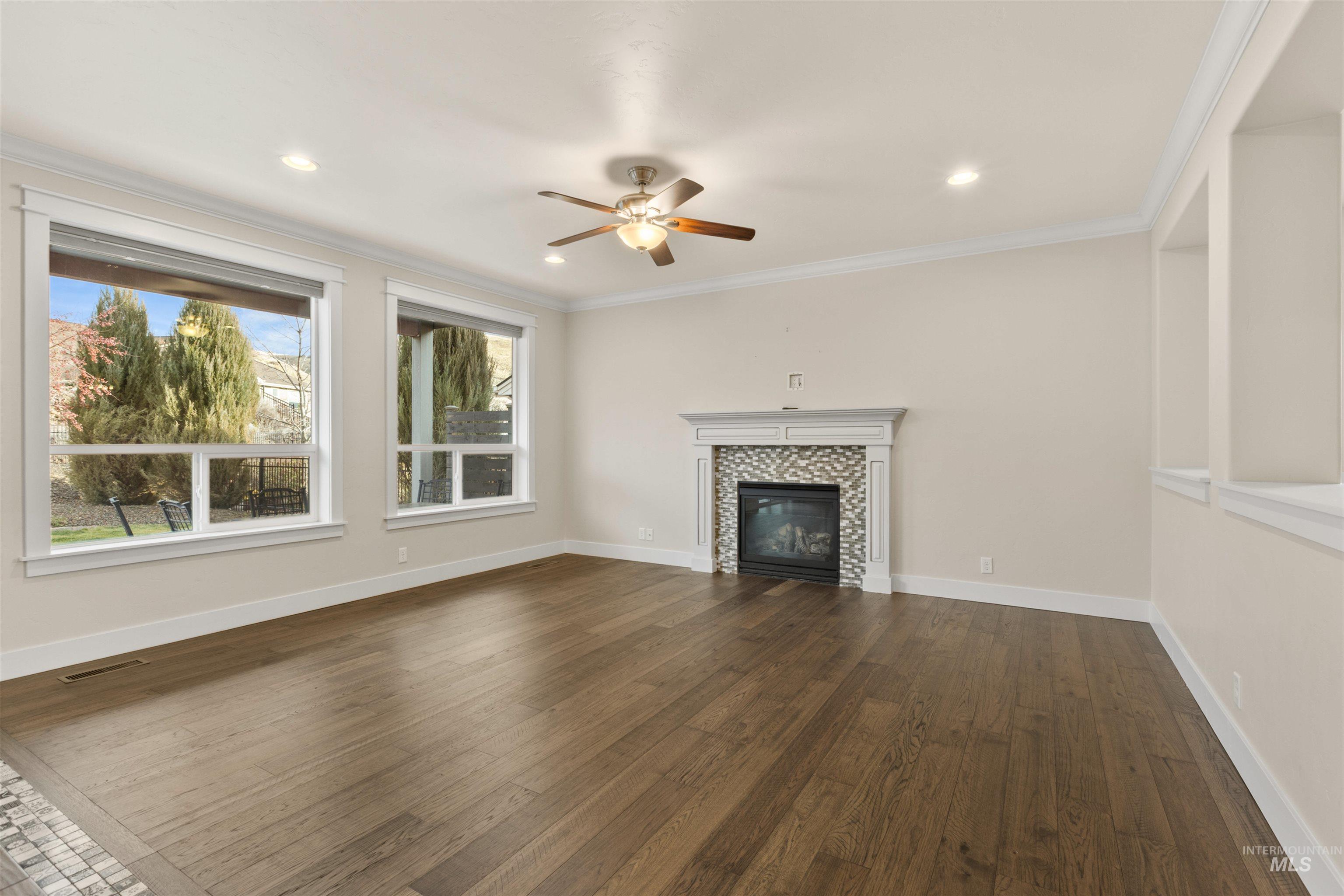 18018 North Streams Edge Way Boise, ID 83714 - Photo 19 of 50 Unfurnished living room featuring dark wood-style flooring, crown molding, a tile fireplace, a ceiling fan, and recessed lighting