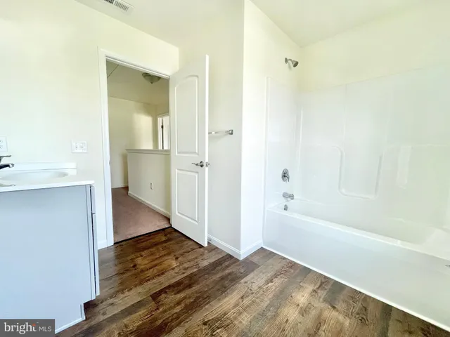 a view of bathroom with bathtub wooden floor and windows