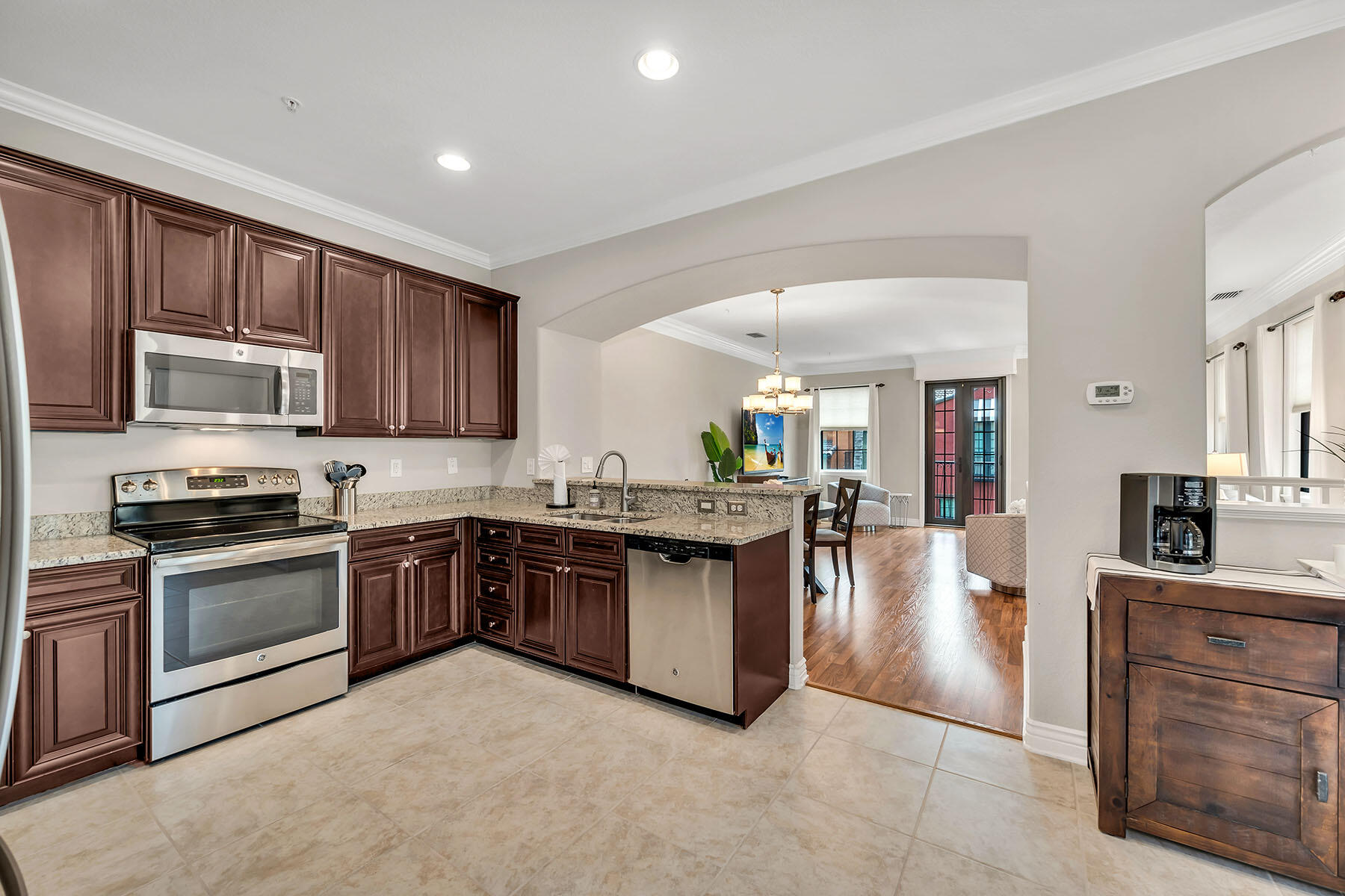 9066 Albion Lane North, Unit 5101 Naples, FL 34113 - Photo 11 of 48 a kitchen with stainless steel appliances granite countertop a stove top oven a sink dishwasher a dining table and chairs with wooden floor