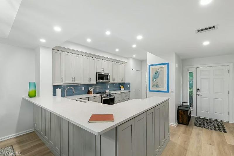 310 La Peninsula Boulevard, Unit 310 Naples, FL 34113 - Photo 4 of 27 a kitchen with stainless steel appliances kitchen island granite countertop a sink and cabinets