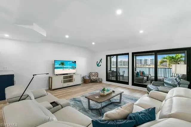 a living room with furniture flat screen tv and a large window