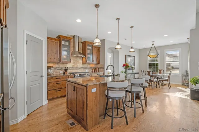 a kitchen with stainless steel appliances kitchen island granite countertop a stove a sink and white cabinets with wooden floor