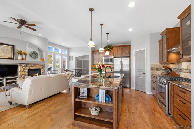 a view of a dining room and livingroom with furniture wooden floor a rug a fireplace and a chandelier