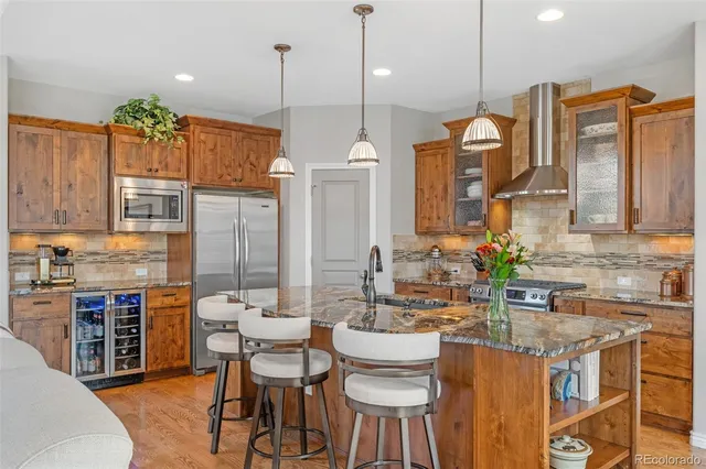 a kitchen with stainless steel appliances granite countertop a stove a sink a refrigerator a center island a dining table and chairs