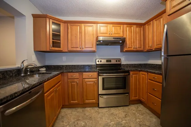a kitchen with stainless steel appliances granite countertop a sink stove and refrigerator