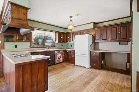 a kitchen with stainless steel appliances granite countertop a refrigerator a sink dishwasher a stove and a dining table with wooden floor