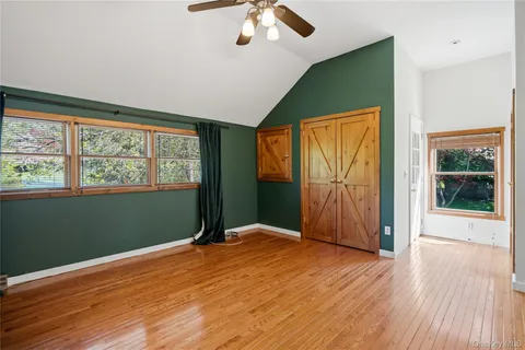 a view of empty room with wooden floor and fan
