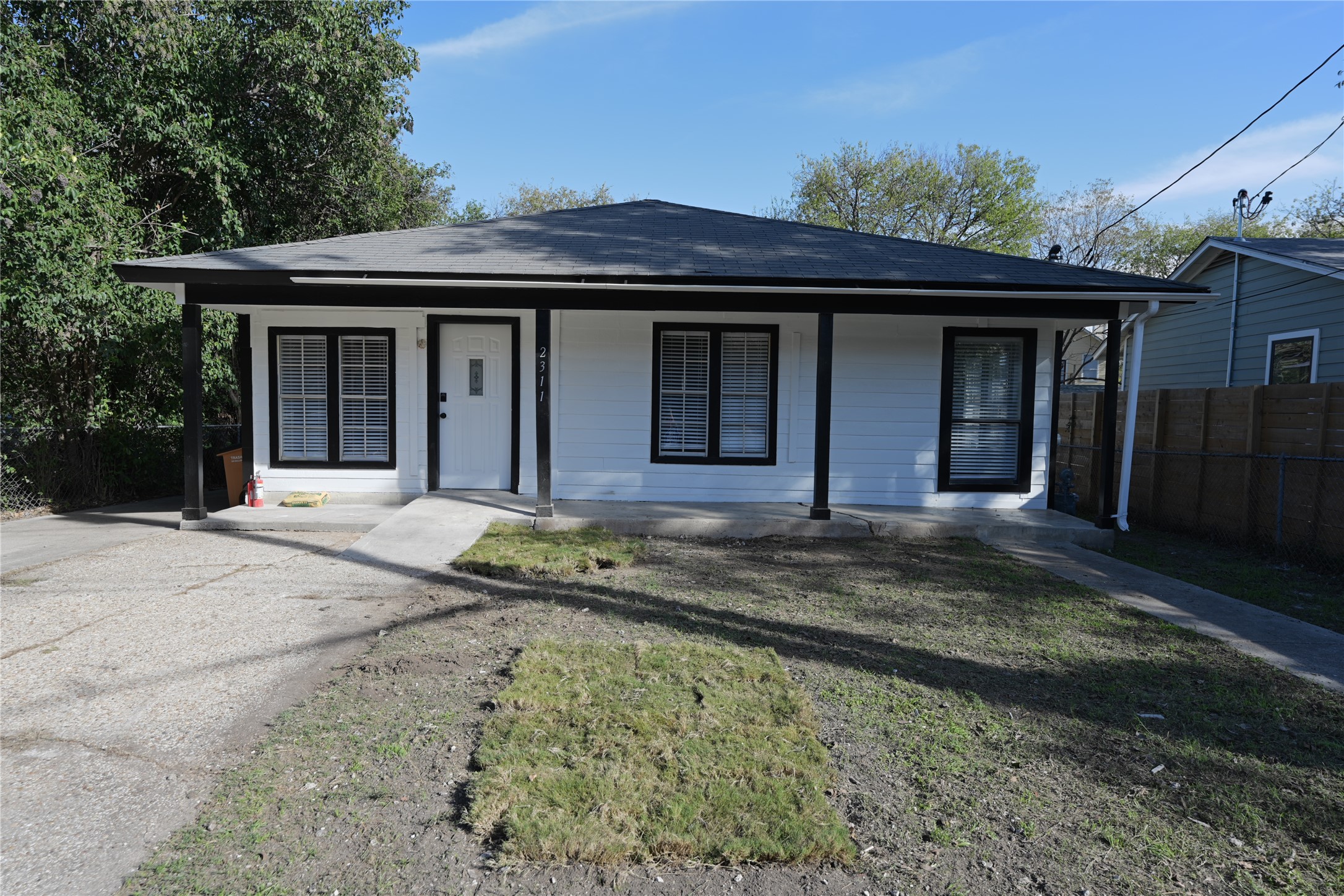 2311 South 3rd Street Austin, TX 78704 - Photo 13 of 14 Front exterior featuring white siding with black trim, a covered porch with black support columns, and a paved driveway