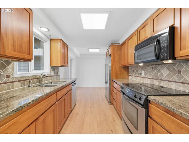 a kitchen with stainless steel appliances granite countertop a sink a stove and a microwave