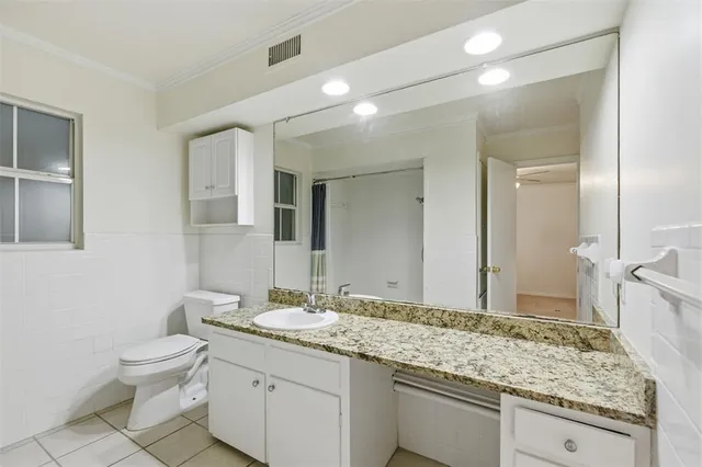 a bathroom with a granite countertop sink a toilet and a mirror