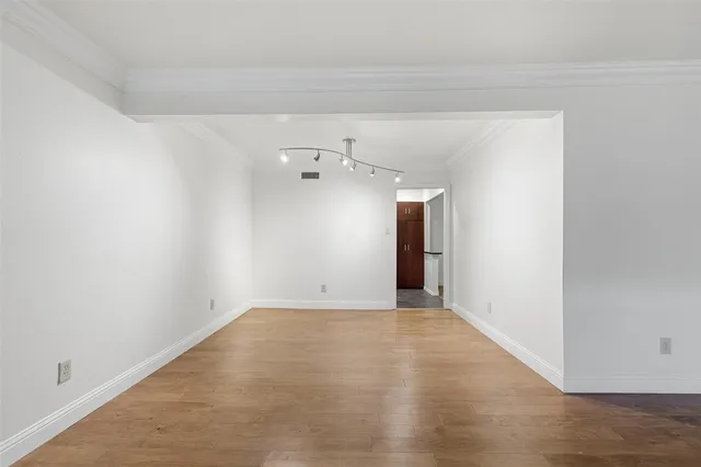 a view of a big room with wooden floor and windows