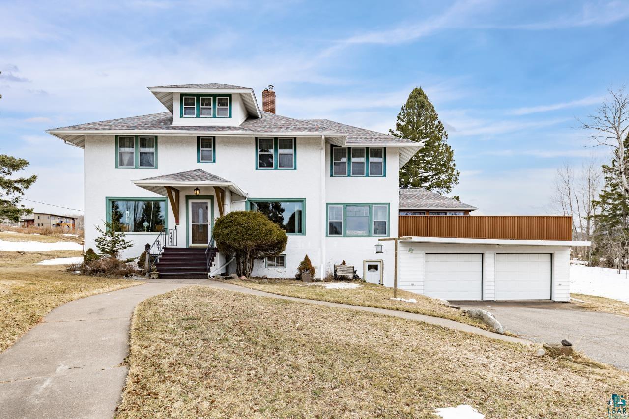 American foursquare style home featuring stucco siding, a chimney, a garage, and a shingled roof