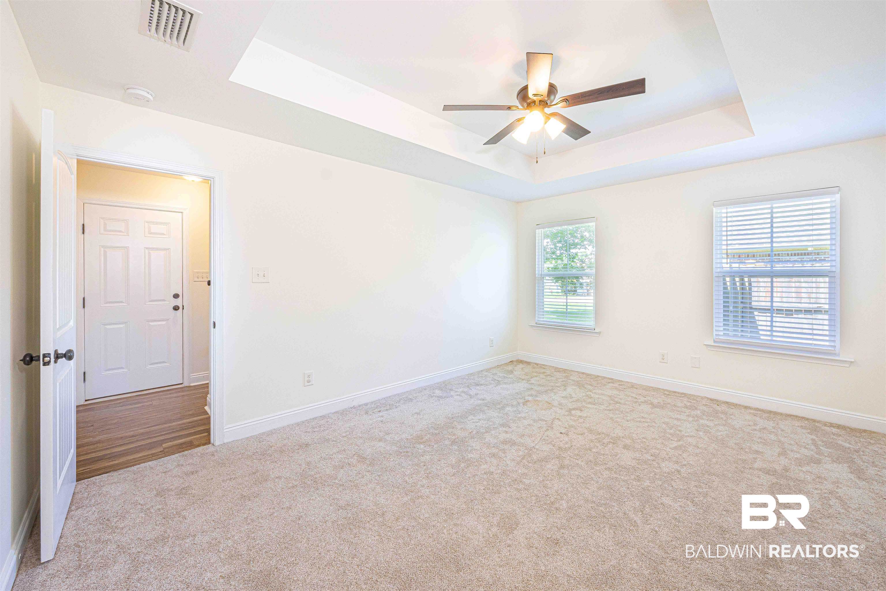 18675 Explorer Drive Loxley, AL 36551 - Photo 19 of 42 Carpeted empty room with a ceiling fan, a raised ceiling, and baseboards