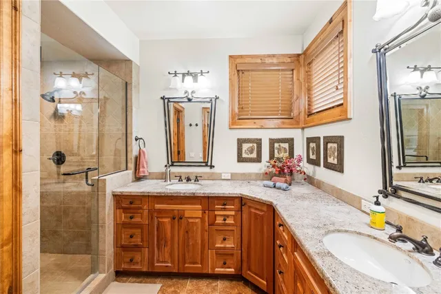 a bathroom with a granite countertop double vanity sink and a mirror