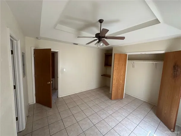an empty room with closet and a ceiling fan