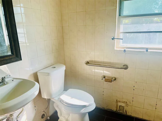 a white toilet sitting next to a bathroom sink and a window