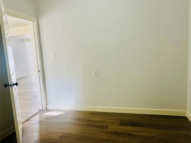 an empty room with wooden floor and entrance
