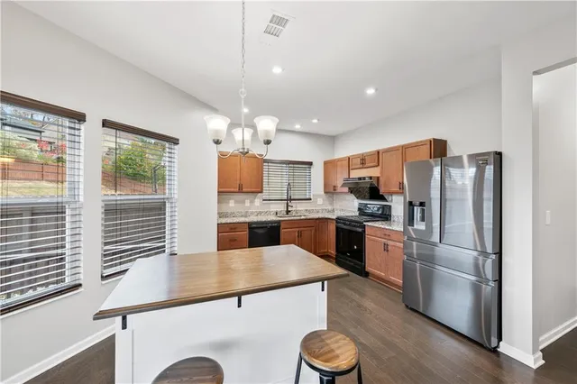 a kitchen with a refrigerator a stove top oven a sink dishwasher and wooden cabinets with wooden floor