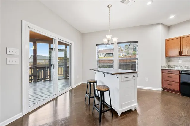 a kitchen with stainless steel appliances granite countertop a stove top oven a sink a dining table and chairs with wooden floor