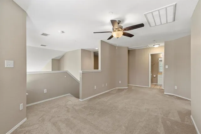 an empty room with ceiling fan and windows