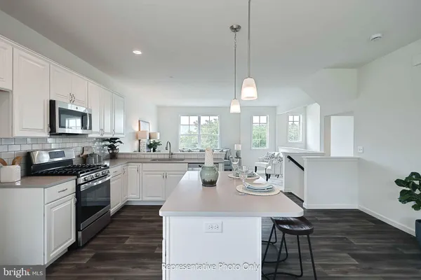 a kitchen with stainless steel appliances granite countertop a stove top oven a sink dishwasher a dining table and chairs with wooden floor