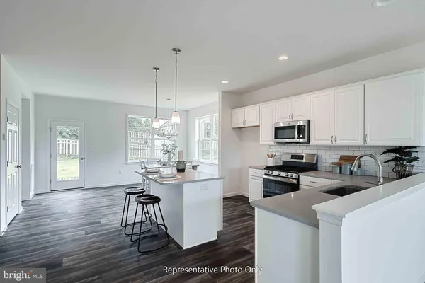 a kitchen with stainless steel appliances kitchen island granite countertop a sink cabinets and wooden floor