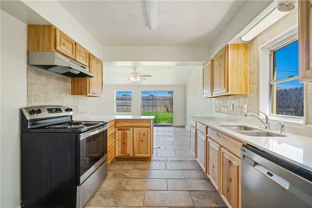 a kitchen with stainless steel appliances granite countertop a stove a sink and a refrigerator