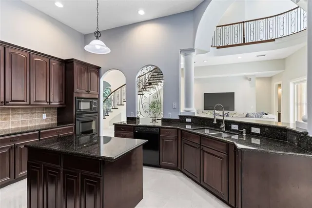 a large kitchen with granite countertop a large counter top cabinets appliances and a ceiling fan
