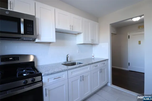 a kitchen with granite countertop white cabinets and black appliances