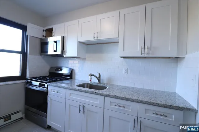 a kitchen with granite countertop a sink dishwasher stove and cabinets