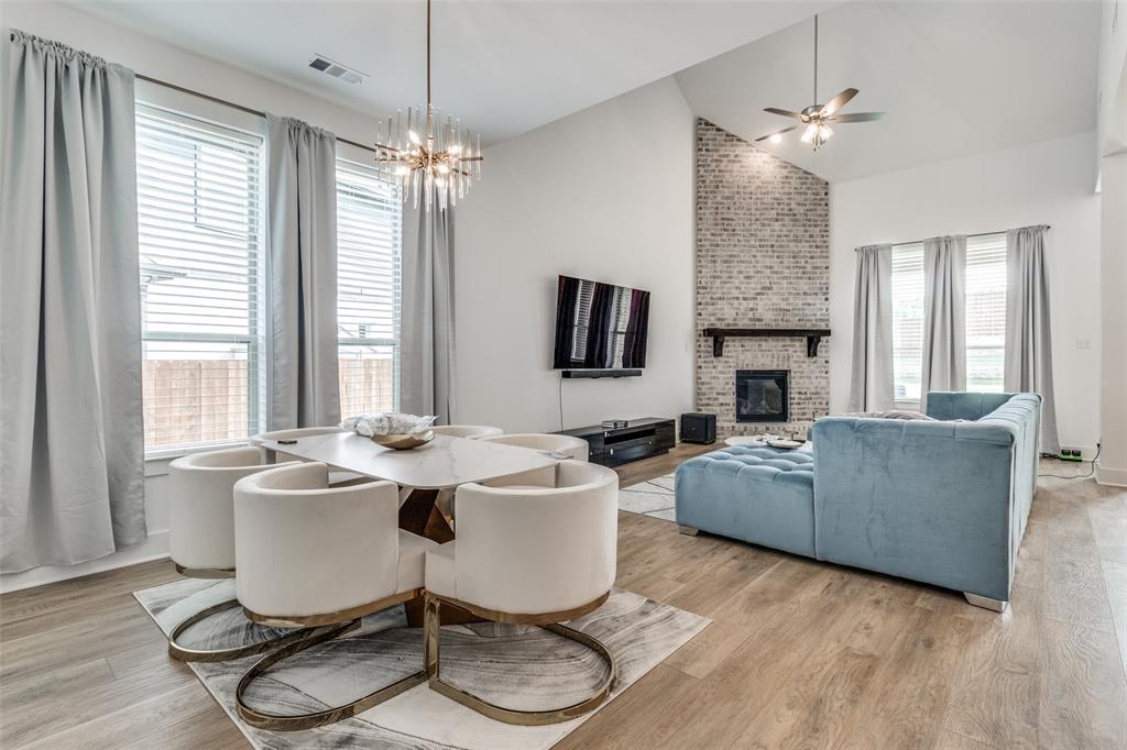503 North Eagle Pt Road Van Alstyne, TX 75495 - Photo 4 of 25 Dining space featuring a brick fireplace, light wood-type flooring, a ceiling fan, a chandelier, and high vaulted ceiling